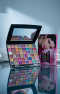 Makeup palette with colorful shades and a mirror, displayed on a reflective surface.