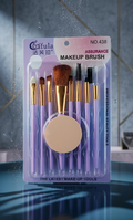 Set of makeup brushes in a clear plastic packaging with a purple label on a reflective surface.