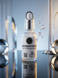 A frosted glass skincare dropper bottle labeled SKINSATTION Clear & Radiant Infuser, with a silver pump cap, shown on a reflective surface with decorative glass spheres and floating bubbles in a polished studio setting.