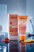 XCM PureActive skincare product on a reflective surface with pomegranate and orange slices.